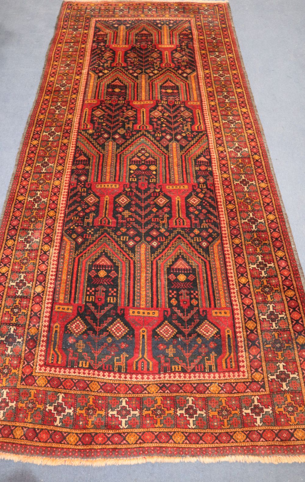An Afghan red ground rug, 310 x 136cm